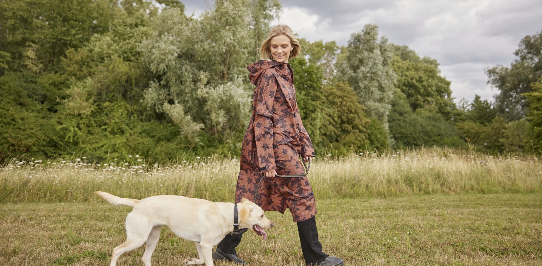 Femme portant un poncho Rainkiss promenant son chien